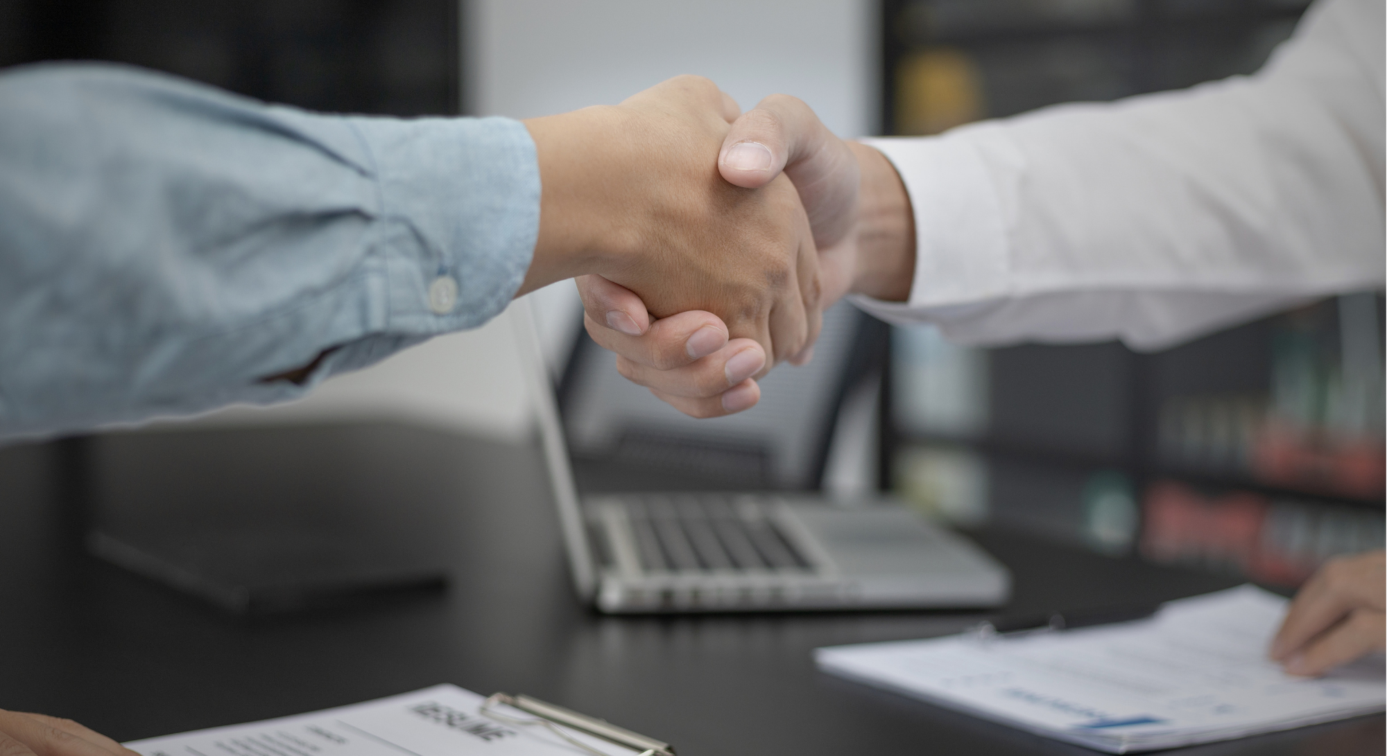 Aperto de mãos em reunião empresarial representando contratação de prestação de serviços e formalização de parceria profissional